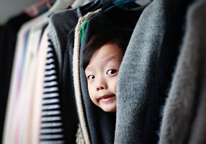Child playing hide and seek in the wardrobe