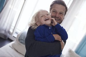 Papa hält Kind und Kind lacht