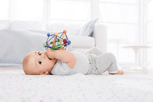baby lying on back with toy in mouth