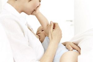 mother breast feeding baby and babys arm on mothers mouth