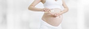 Schwangere cremt ihren Bauch ein