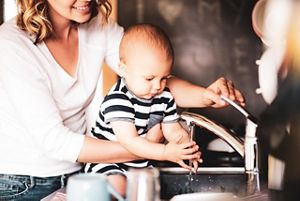 Kind wäscht Hände mit Mama