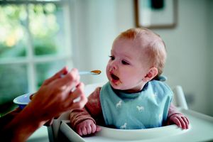 mother spoon feeding toddler