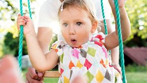Toddler On Swings With Parent