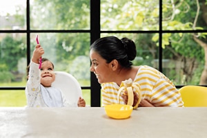 toddler-with-mother-eating-banana-puree.png