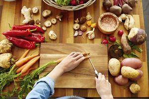 Point of view shot of woman cutting carrots on wooden board