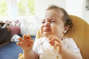 Unhappy Baby In High Chair At Meal Time
