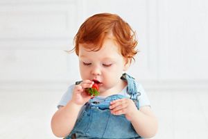 Rothaariges Baby nascht Erdbeere