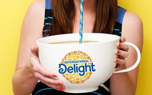 Femme buvant à la paille un produit International Delight dans une grande tasse Femme buvant à la paille un produit International Delight dans une grande tasse